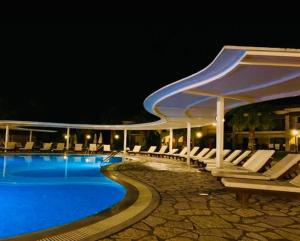 a swimming pool with white chairs and a largevisorricularricularricularricularricularricular at Perdika Resort in Perdika