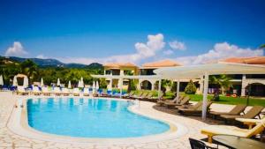 a pool at a resort with chairs and umbrellas at Perdika Resort in Perdika