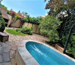 a swimming pool in a yard with trees and flowers at Alamo Hostel & Suites in Mendoza