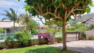 a tree in a yard with a fence and flowers at Praia Brava Apto 2 dorms Vista ao Mar in Florianópolis