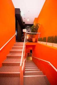 a stairway with orange walls and stairs with plants at SleepBox Hostel in Taipei
