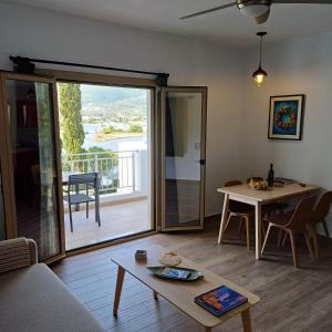 ein Wohnzimmer mit einem Tisch und einer Glasschiebetür in der Unterkunft Skiathos Lagoterra Apartments in Skiathos-Stadt