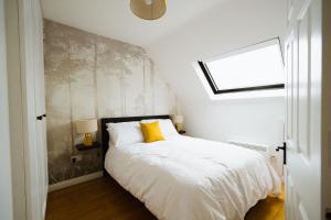 Un dormitorio con una cama blanca con una almohada amarilla. en The Hive, en Galway 5 fotos más