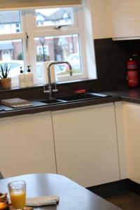 - une cuisine avec un évier et un verre de jus d'orange dans l'établissement Charming 3 Bedroom Apartment in Wythenshawe Convenient for Manchester Airport and City Centre Free Parking, à Wythenshawe