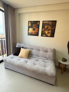 a white couch in a living room with paintings on the wall at Paradise at your fingertips in Cabedelo
