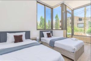 two beds in a room with large windows at Yara's 2BR Terrace Retreat in Fārayyā