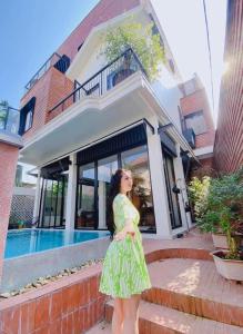 a woman in a green dress standing in front of a house at Florence Villa Hue in Hue