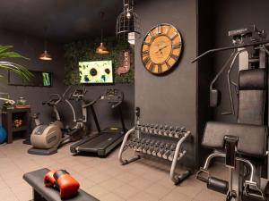 a gym with cardio equipment and a clock on the wall at Novotel Barcelona City in Barcelona