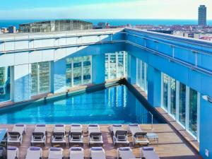 a swimming pool on the roof of a building with lounge chairs at Novotel Barcelona City in Barcelona