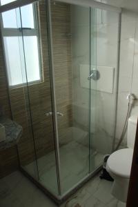 une douche en verre dans une salle de bains avec toilettes dans l'établissement Flat Makaranduba Centro Porto de Galinhas,dois quartos, à Porto de Galinhas 32 autres photos