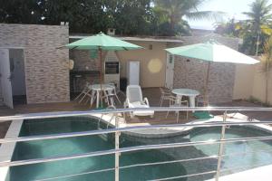 une piscine avec un parasol, une table et des chaises dans l'établissement Flat Makaranduba Centro Porto de Galinhas,dois quartos, à Porto de Galinhas