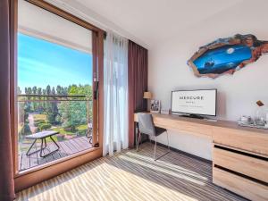 a room with a desk with a television and a balcony at Mercure Gdańsk Posejdon in Gdańsk