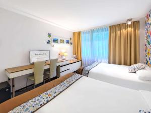 a hotel room with two beds and a desk at Mercure Gdańsk Posejdon in Gdańsk