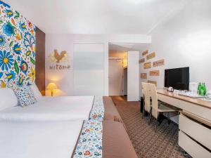 a hotel room with a bed and a desk with a computer at Mercure Gdańsk Posejdon in Gdańsk