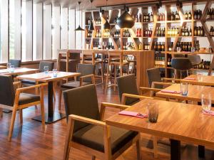 a restaurant with wooden tables and chairs and wine bottles at Mercure Gdańsk Posejdon in Gdańsk