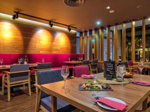a restaurant with a wooden table and chairs and pink booths at Mercure Gdańsk Posejdon in Gdańsk