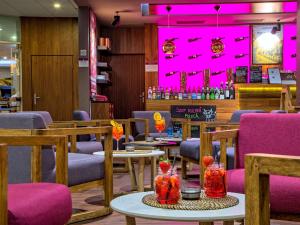 a restaurant with purple chairs and tables with drinks at Mercure Gdańsk Posejdon in Gdańsk