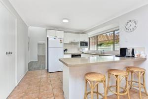 a kitchen with white appliances and stools at The Fingal Escape in Fingal Bay