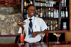 een man in een wit shirt en stropdas zittend aan een bar bij Zanzibar Ocean View Hotel in Zanzibar City