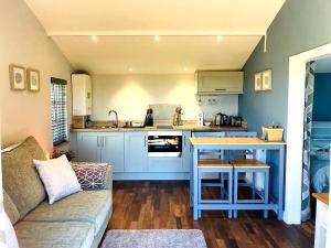 a living room with a couch and a kitchen at Honeysuckle Cabin in Redruth