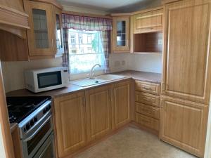 a kitchen with wooden cabinets and a microwave at Ferienhaus im Villengarten in Neustadt am Kulm