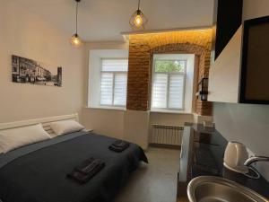 a bedroom with a bed and a sink and two windows at St Benedict Apartments in Lviv