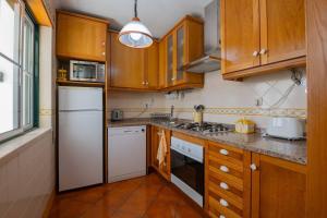 eine Küche mit Holzschränken und einem weißen Kühlschrank in der Unterkunft Milfontes' Shelter in Vila Nova de Milfontes
