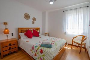 ein Schlafzimmer mit einem Bett mit roten Kissen und einem Stuhl in der Unterkunft Milfontes' Shelter in Vila Nova de Milfontes