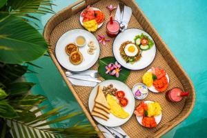 a table with plates of breakfast food on a tray at Villa Lemone Braban by Bali Villa Solutions in Seminyak