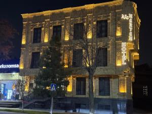 Un edificio con luces en el costado. en AL MARYAM HoteL, en Samarkand