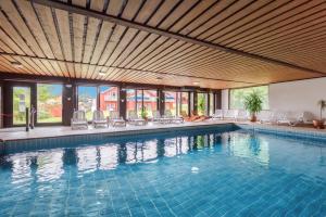 a large swimming pool with a wooden ceiling at Village Hotel Bayerischer Wald in Neukirchen