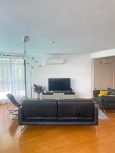 a living room with a black couch and a tv at Great V4 Villa with Private Salt Pool in Quinta do Anjo