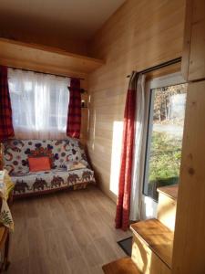a small room with a couch in a cabin with a window at Tiny House lumineuse et ressourçant in Le Brusquet