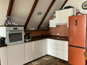 a kitchen with white cabinets and an orange refrigerator at Elbblick Schnackenburg in Schnackenburg