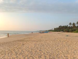a person standing on a beach with a boat at Green Villa Ahungalla in Balapitiya
