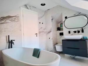 a bathroom with a tub and a sink and a mirror at Tudisi Loft Room in Dubrovnik