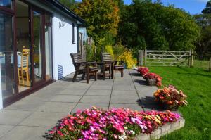 een patio met een tafel, stoelen en bloemen bij Smithfield Farm Bed & Breakfast in Builth Wells