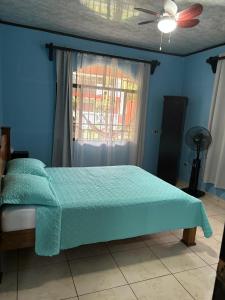a bed in a blue bedroom with a ceiling fan at Villa tico House in Cariari +48 photos