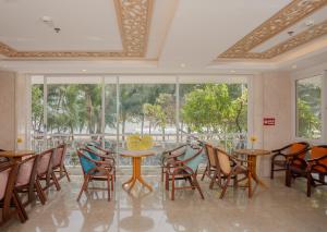 a dining room with tables and chairs and windows at Nang Vang Hotel Nha Trang in Nha Trang