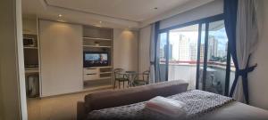 a bedroom with a couch and a window with a view at Bienal Suites Ibirapuera c/ Sacada - UH 1207 in São Paulo