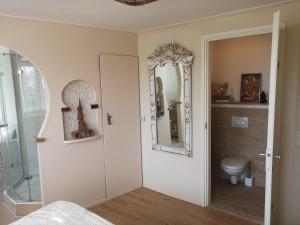 a bathroom with a toilet and a mirror at Modern Cozy Asian Style bedroom with Kingsize Spa bath in Westbeemster