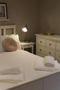 a bedroom with a white bed with a lamp and a dresser at The Nook in Bakewell +29 photos