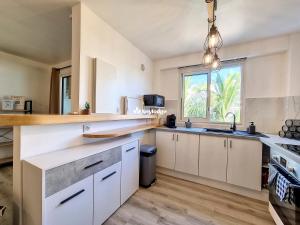 a large kitchen with white cabinets and a window at Valeriane, classé 3 étoiles - T2 de 45 m2 à Sainte-Clotilde in Saint-Denis +19 photos