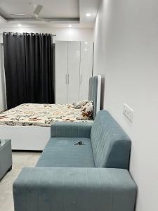 a bedroom with a bed and a blue couch at Golden palace studio in Noida