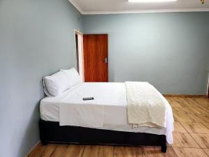 モコパネにあるMajestic Guest Houseのベッドルーム1室(白いシーツ付きのベッド1台、木製のドア付)