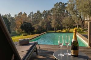 a bottle of wine sitting on a table next to two wine glasses at Portugal Active São Julião Retreat | Pool, Jacuzzi & Garden Escape in Mato