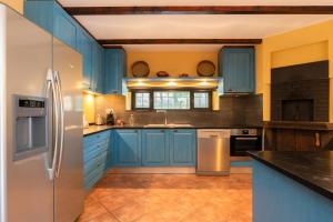a kitchen with blue cabinets and a stainless steel refrigerator at Portugal Active São Julião Retreat | Pool, Jacuzzi & Garden Escape in Mato +202 photos