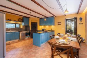 a kitchen with blue cabinets and a wooden table at Portugal Active São Julião Retreat | Pool, Jacuzzi & Garden Escape in Mato