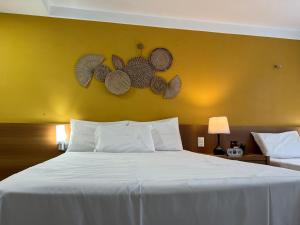 a bedroom with a large white bed with a yellow wall at PONTA NEGRA FLAT APART in Natal +127 photos