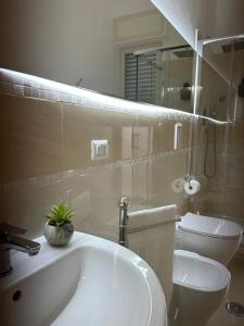 un bagno con lavandino, WC e specchio di Casa Rosa a Poggiomarino Altre 8 foto